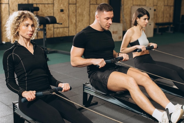 Giovane e belle donne che lavorano con il vogatore in palestra crossfit