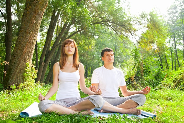 Giovane e donna che fanno yoga in giardino