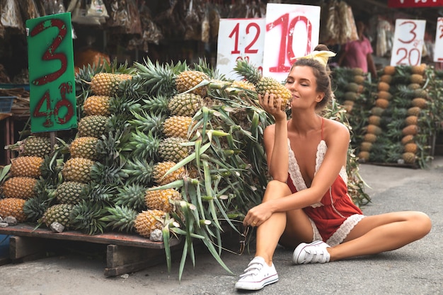 Giovane e donna felice con un mucchio di ananas al mercato