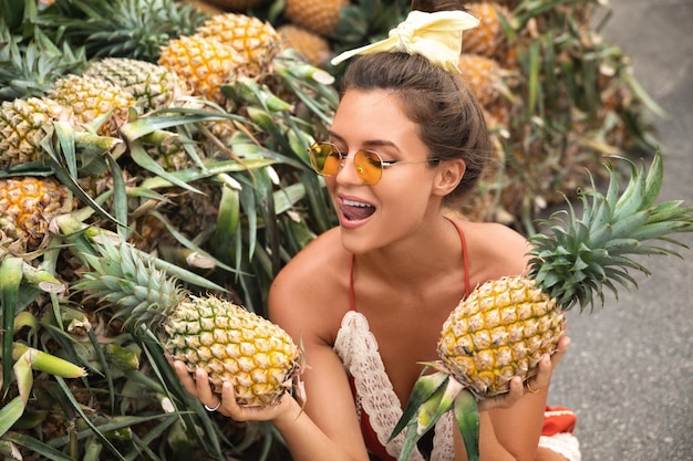 Giovane e donna felice con un mucchio di ananas al mercato
