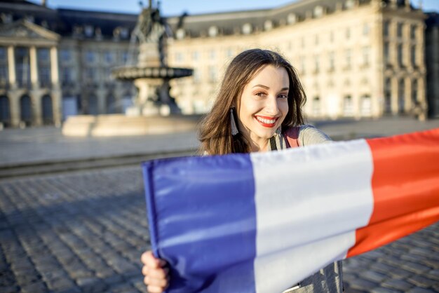 Giovane e felice turista che tiene bandiera francese nella città di Bordeaux in Francia