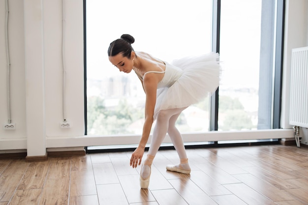 Giovane e graziosa ballerina che prova l'esibizione nella sala bianca.