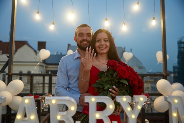 Giovane e la sua fidanzata felice che mostra l'anello di fidanzamento