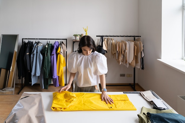Giovane e moderna sarta ragazza vestiti fogna lavoro sulla collezione di impermeabili alla moda in studio atelier