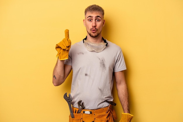 Giovane elettricista uomo caucasico isolato su sfondo giallo che ha qualche grande idea, concetto di creatività.