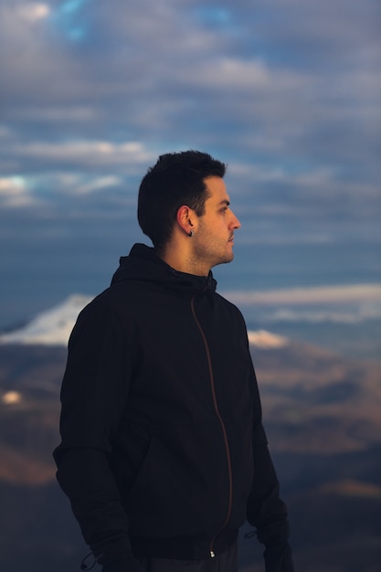 Giovane escursionista in cima a una montagna innevata in inverno.