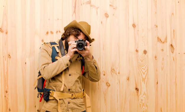 Giovane esploratore pazzo con cappello di paglia e zaino sulla parete di legno