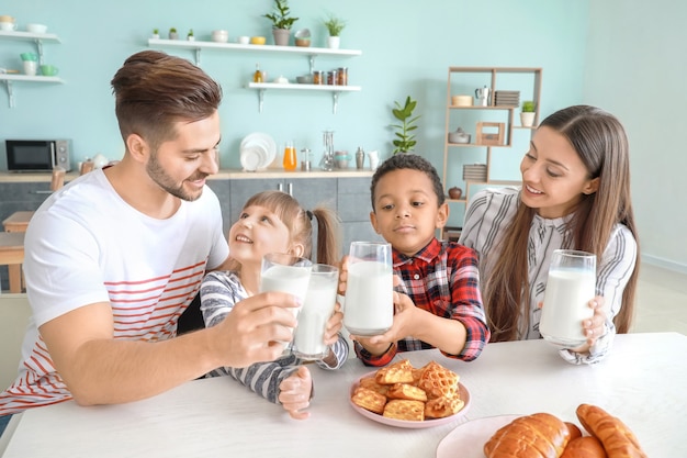 Giovane famiglia che beve latte gustoso in cucina a casa