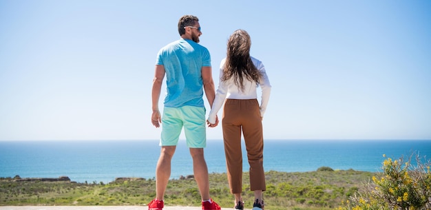 Giovane famiglia che guarda lontano. vacanza di viaggio. uomo e donna felici che si tengono per mano.