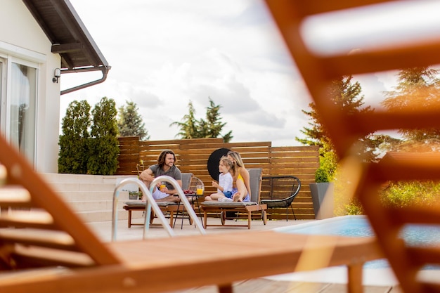 Giovane famiglia che si rilassa a bordo piscina nel cortile della casa