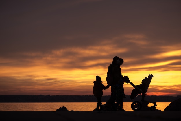 Giovane famiglia che si staglia contro un tramonto sull'oceano