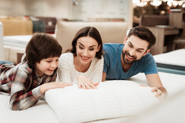 Giovane famiglia che si trova sul cuscino commovente del materasso