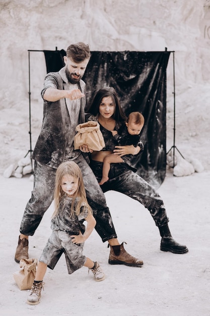 Giovane famiglia con 2 bambini vestiti di nero che posano per una foto durante un servizio fotografico stilizzato in un luogo bianco naturale divertente, elegante e carismatico Famiglia con due figlie