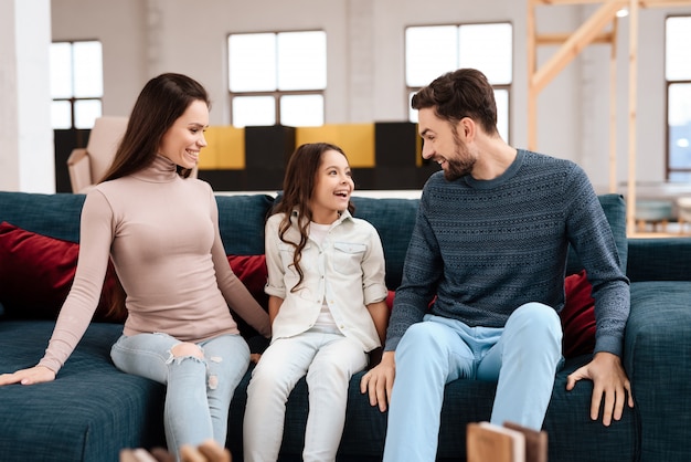 Giovane famiglia con bambina seduta sul divano.