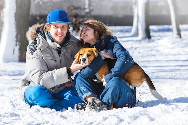 Giovane famiglia, coppia innamorata in una passeggiata invernale con un cucciolo di beagle.