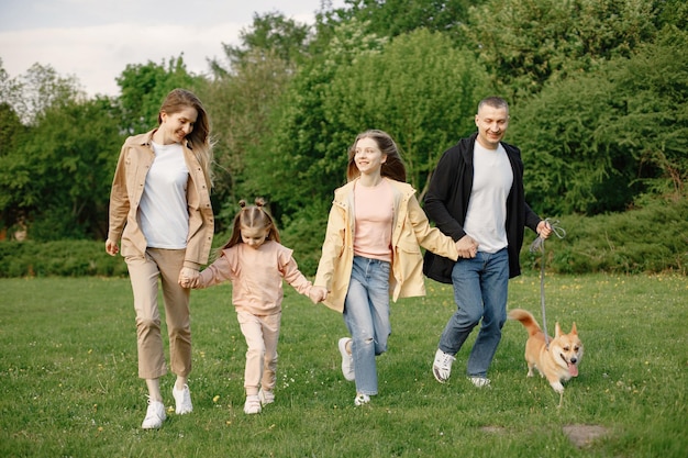 Giovane famiglia e il loro cane corgi che camminano insieme in un parco