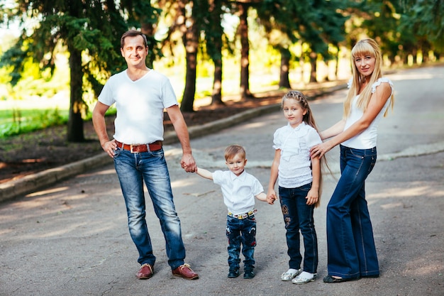 Giovane famiglia felice che cammina lungo la strada fuori in natura verde.