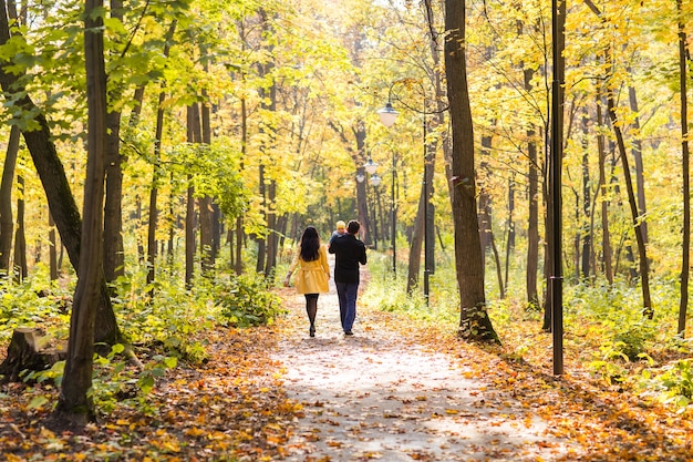 Giovane famiglia felice che cammina per strada fuori nella natura autunnale