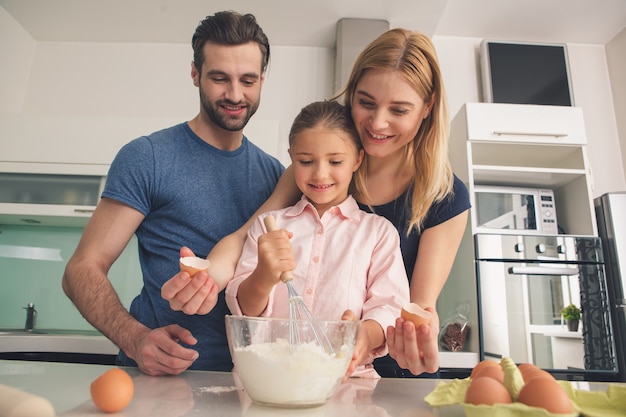 Giovane famiglia felice che cucina la pasta insieme mescolando