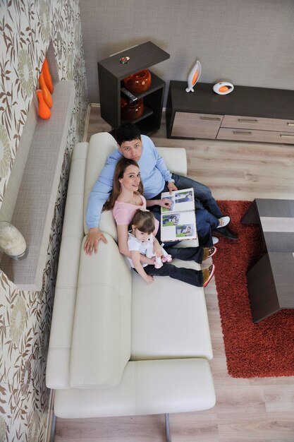 giovane famiglia felice che guarda vecchie foto nell'album fotografico a casa