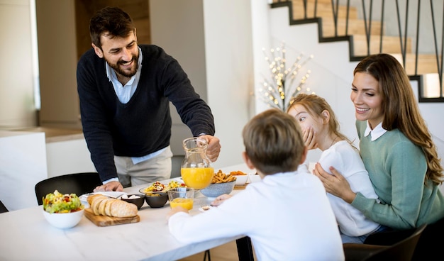 Giovane famiglia felice che parla mentre si fa colazione al tavolo da pranzo dell'appartamento