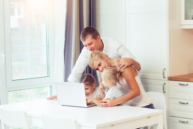 Giovane famiglia felice che usa il laptop mentre è seduto in cucina a casa