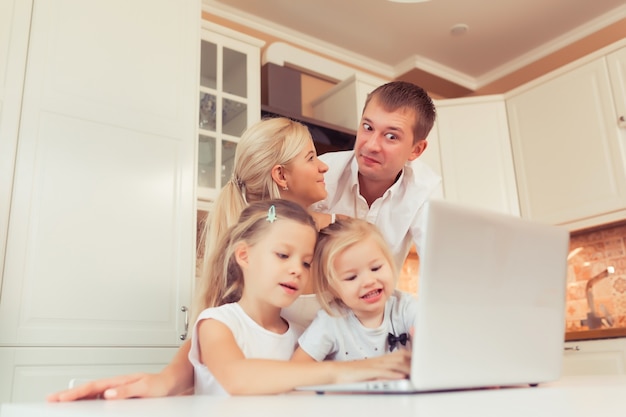 Giovane famiglia felice che usa il laptop mentre è seduto in cucina a casa