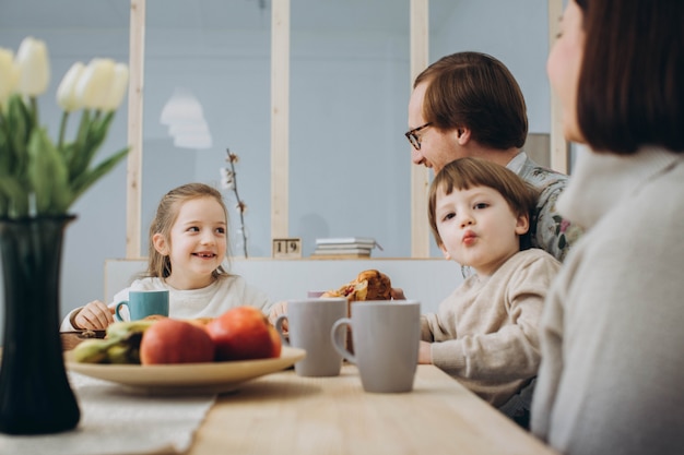 Giovane famiglia felice con due bambini facendo colazione insieme.