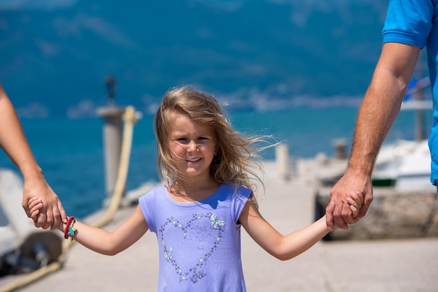 giovane famiglia felice con graziose figlie che si tengono per mano mentre si cammina in riva al mare durante le vacanze estive Concetto di vacanza in famiglia sana