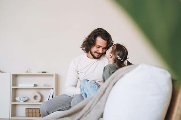 Giovane famiglia felice con padre e figlia sul divano in un'accogliente festa del papà a casa