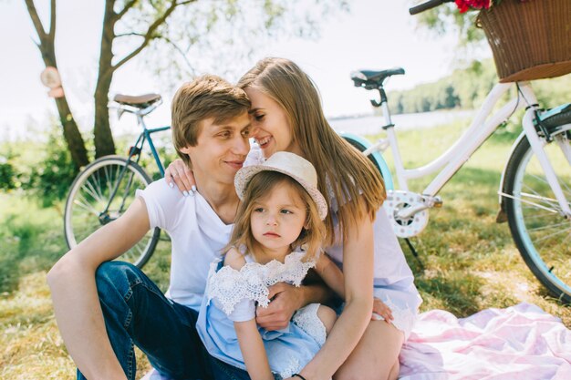 Giovane famiglia felice di trascorrere del tempo insieme fuori. Generi la madre ed il loro bambino nel parco verde su un picnic