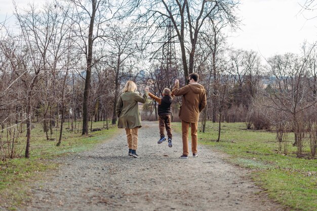 Giovane famiglia felice padre madre e figlio. vista da dietro. a piedi dal parco cittadino