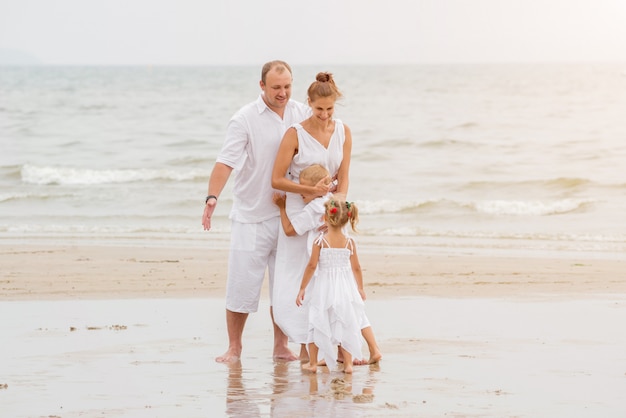 Giovane famiglia felice sul tramonto sulla spiaggia.