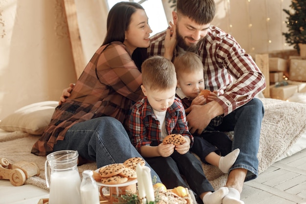 Giovane famiglia in camicie a quadri che mangia biscotti e abbraccia