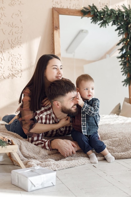 Giovane famiglia in camicie a quadri sdraiata su una coperta e abbracciata