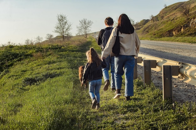 giovane famiglia in una passeggiata lungo la strada con un cane