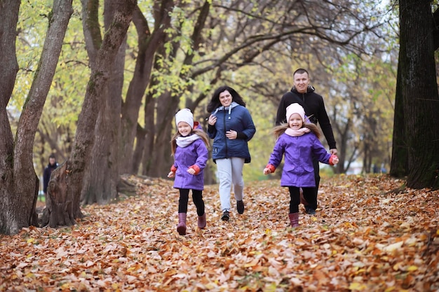 Giovane famiglia in una passeggiata nel parco autunnale in una giornata di sole. Felicità di stare insieme.