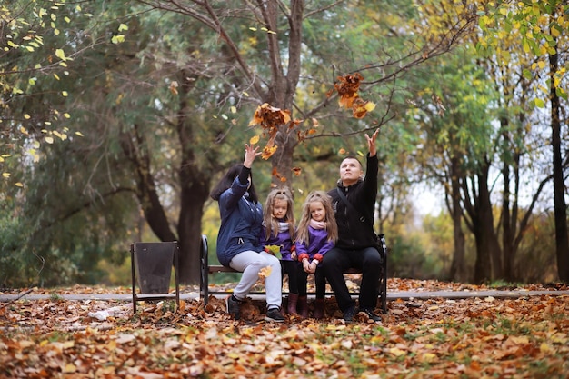 Giovane famiglia in una passeggiata nel parco autunnale in una giornata di sole. Felicità di stare insieme.