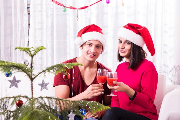 Giovane famiglia indiana asiatica che celebra il Natale con un regalo mentre indossa il cappello di Babbo Natale