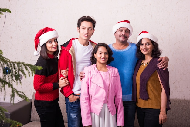 Giovane famiglia indiana asiatica che celebra il Natale con un regalo mentre indossa il cappello di Babbo Natale