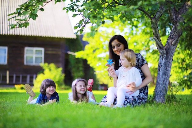 Giovane famiglia numerosa in una passeggiata mattutina estiva. La bella madre con i bambini sta giocando nel parco.