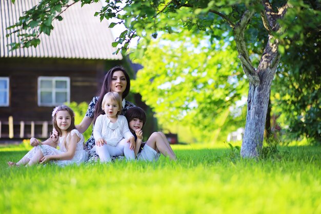 Giovane famiglia numerosa in una passeggiata mattutina estiva. La bella madre con i bambini sta giocando nel parco.