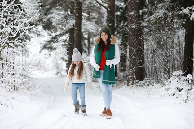 Giovane famiglia per una passeggiata. Mamma e figlia stanno camminando in un parco invernale.