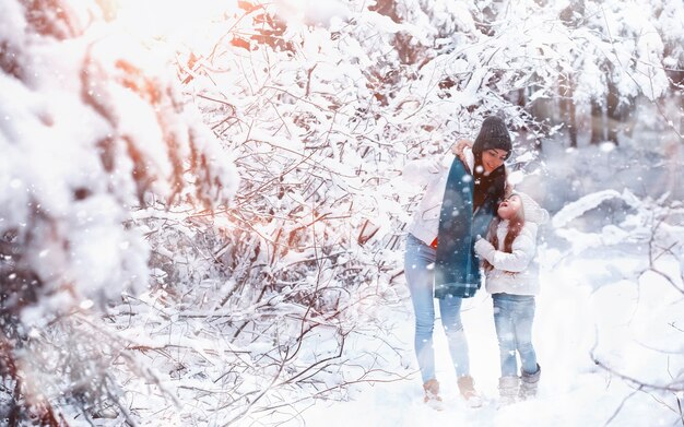 Giovane famiglia per una passeggiata. Mamma e figlia stanno camminando in un parco invernale.