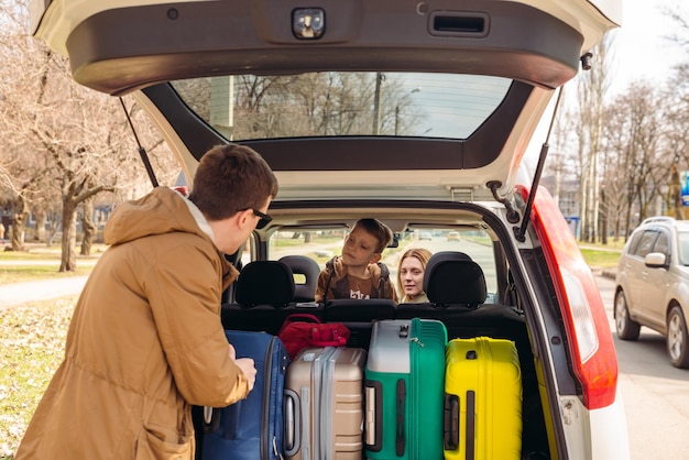 Giovane famiglia pronta per il viaggio in auto bagagliaio pieno di bagagli concetto di viaggio su strada