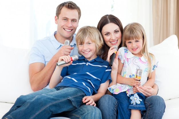 Giovane famiglia sorridente che canta insieme un karaoke