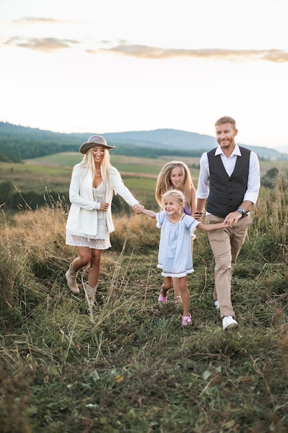 Giovane famiglia sorridente felice con due figlie divertirsi in campagna