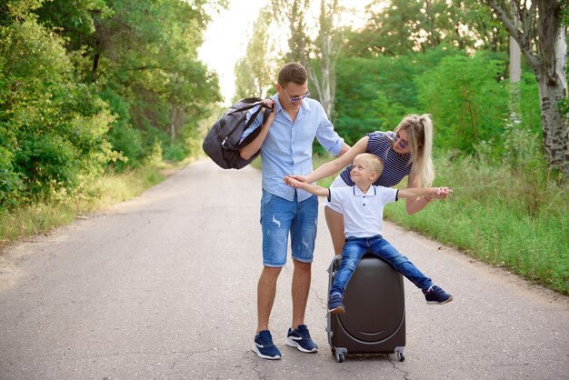 Giovane famiglia viaggiatore intoppo escursionismo su strada vuota.