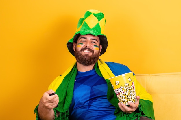 Giovane fan brasiliano che guarda la partita in tv tenendo in mano un telecomando