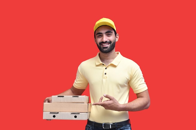 giovane fattorino aspetto frontale in maglietta gialla e berretto con scatole per pizza modello indiano pakistano